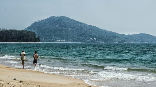 Two people walking on calm beach