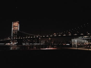 Illuminated bridge over river against sky at night