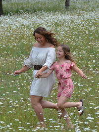 Happy mother and daughter holding hands while running on land