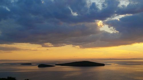 Scenic view of sea against cloudy sky during sunset