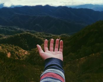 Cropped hand against mountains