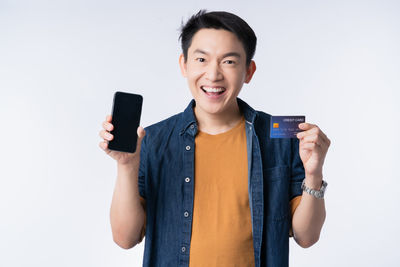 Portrait of smiling young man standing against white background