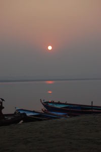 Boats moored on sea against sky during sunset