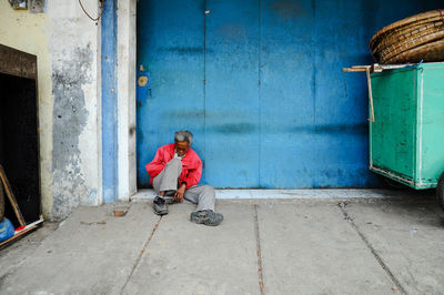 Man with umbrella sitting on street