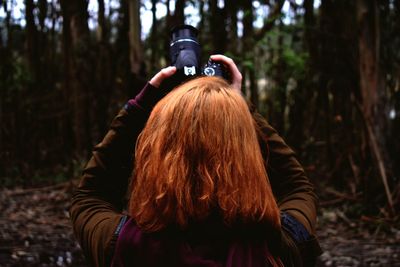 Rear view of woman with arms raised in forest