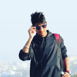 Portrait of young man with sunglasses standing against sky during sunny day