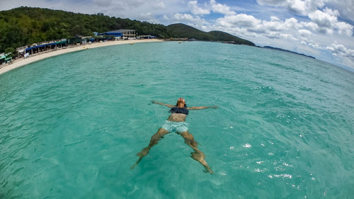 Woman floating in sea against sky