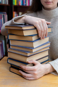 Young woman holds a stack of books close up person