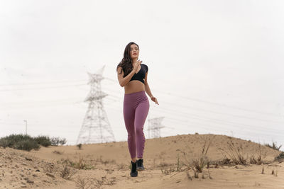 Full length of woman running at beach against clear sky