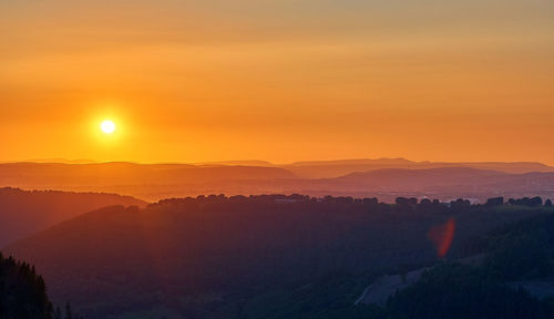 Scenic view of silhouette mountains against orange sky