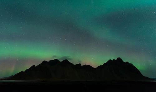 Scenic view of rocky mountains against aurora borealis in sky at night