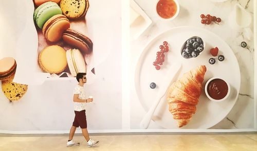 Full length side view of man walking against patterned wall