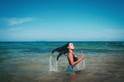 Young woman in sea against sky