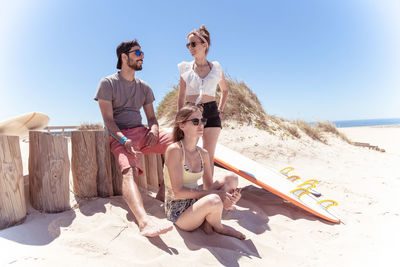 Full length of friends on beach against sky