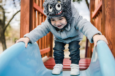 Full length of cute baby boy standing on slide at playground