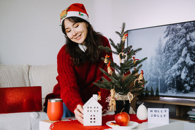 Portrait of smiling young woman holding christmas tree
