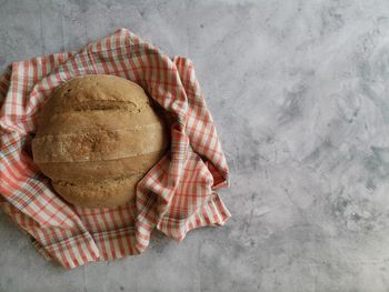 Homemade rye bread in a checkered towel on a gray table