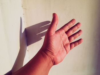 Close-up of hand against white wall