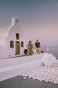 Couple holding hands while standing by church against sky