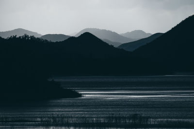 Scenic view of sea and silhouette mountains against sky