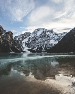Scenic view of frozen lake by snowcapped mountains against sky
