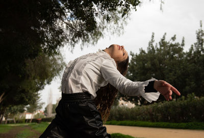 Side view of young man standing against trees