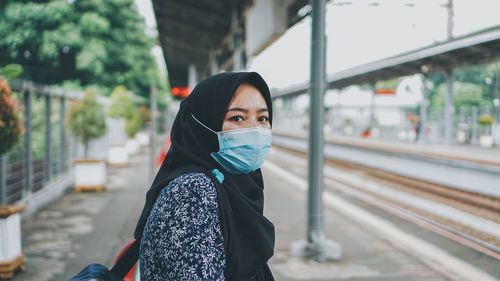 Portrait of young woman standing at railroad station