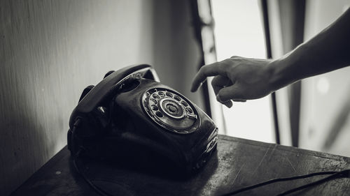 Cropped hand using rotary phone at table