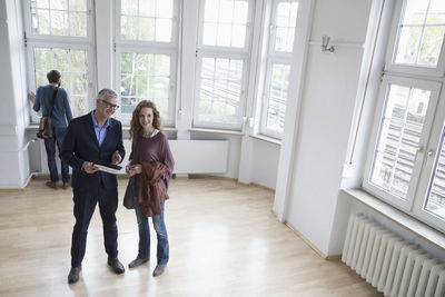 Real estate agent talking to client in empty apartment