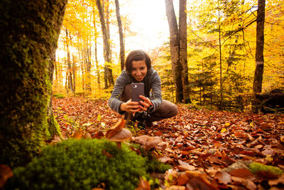 Side view of woman sitting in forest