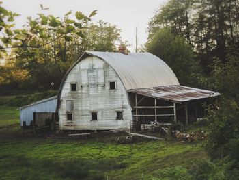 Old barn on field against buildings