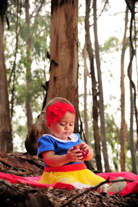 Cute baby girl sitting on tree trunk