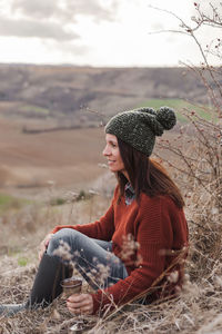 Young woman wearing hat sitting on field