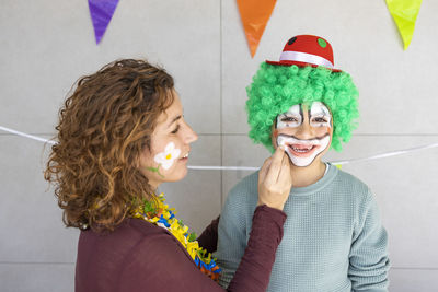 Mother painting her son's face like a clown