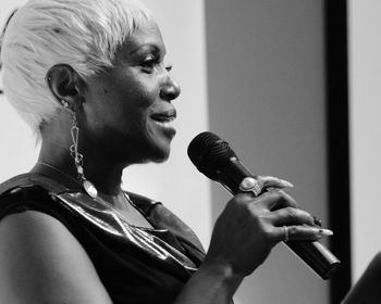 Side view of smiling mature woman singing on microphone during event