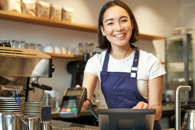 Portrait of young woman standing in cafe