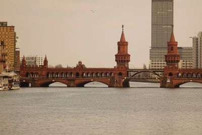 Arch bridge over river against buildings in city