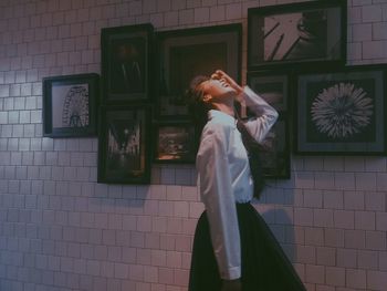 Side view of woman standing against wall