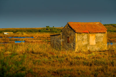 Abandoned house on field against sky