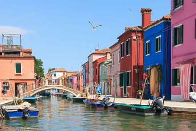 Boats moored on canal by colorful buildings at burano island