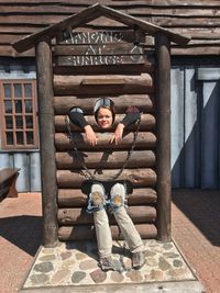 Full length portrait of young woman at wooden structure