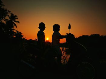 Silhouette men sitting against sky during sunset