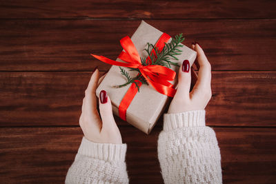 Cropped hands of woman holding gift on table