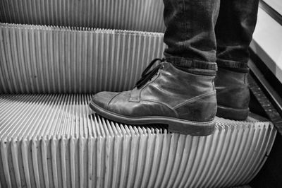 Low section of man wearing shoes standing on escalator