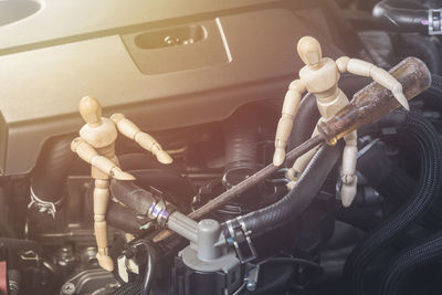 High angle view of figurines with work tools on car engine