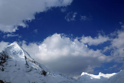 Low angle view of snowcapped mountain against blue sky