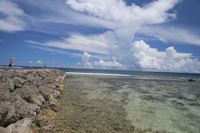 View of calm beach against cloudy sky