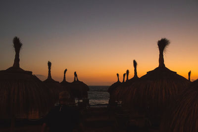 Silhouette people on beach against clear sky during sunset