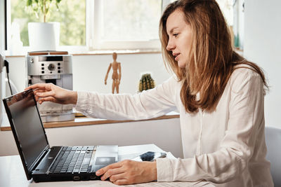 Woman works remotely at home office with laptop