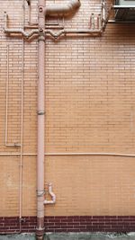 Low angle view of pipe on brick wall